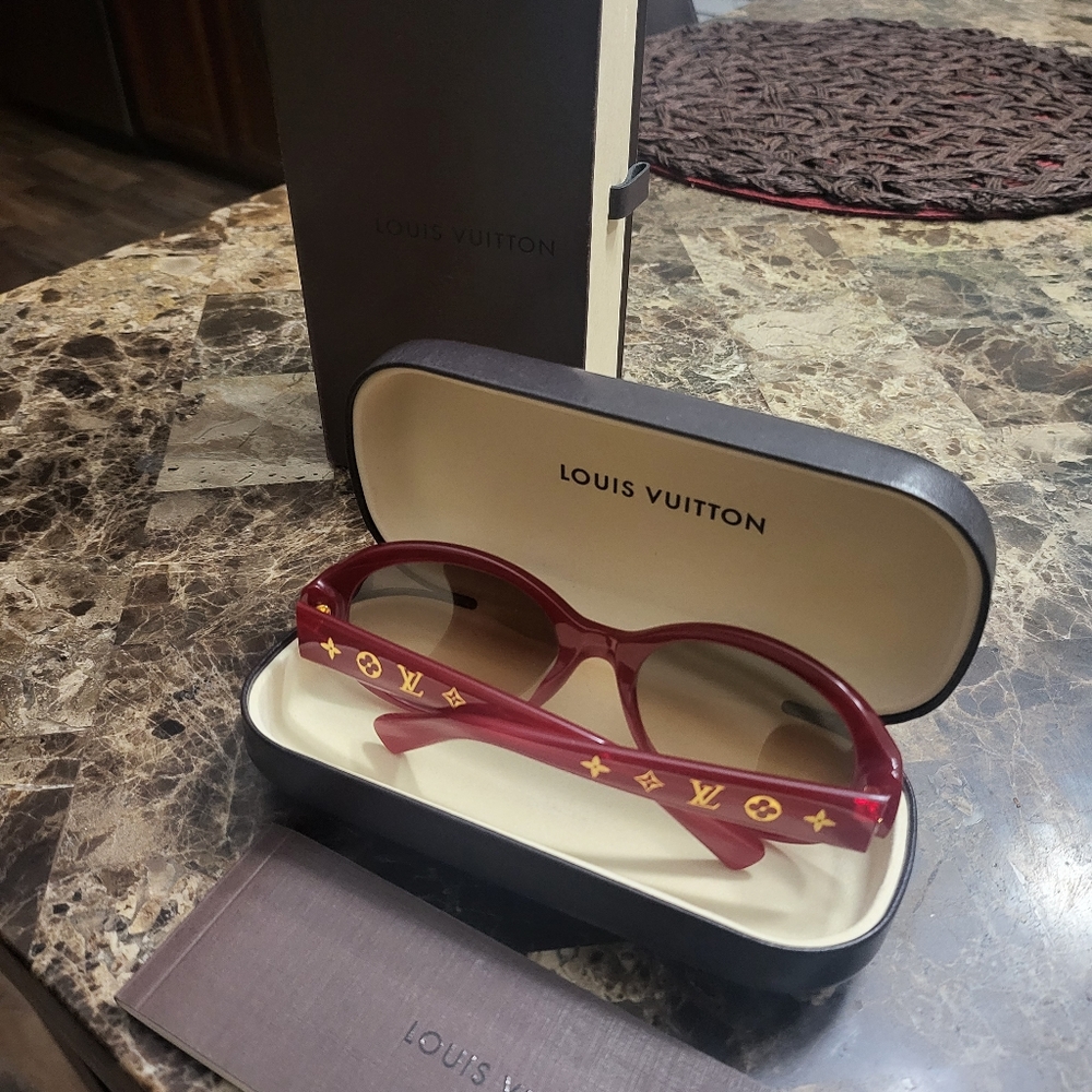 Red sparkle Louis Vuitton sunglasses with the gold symbols on both arms.